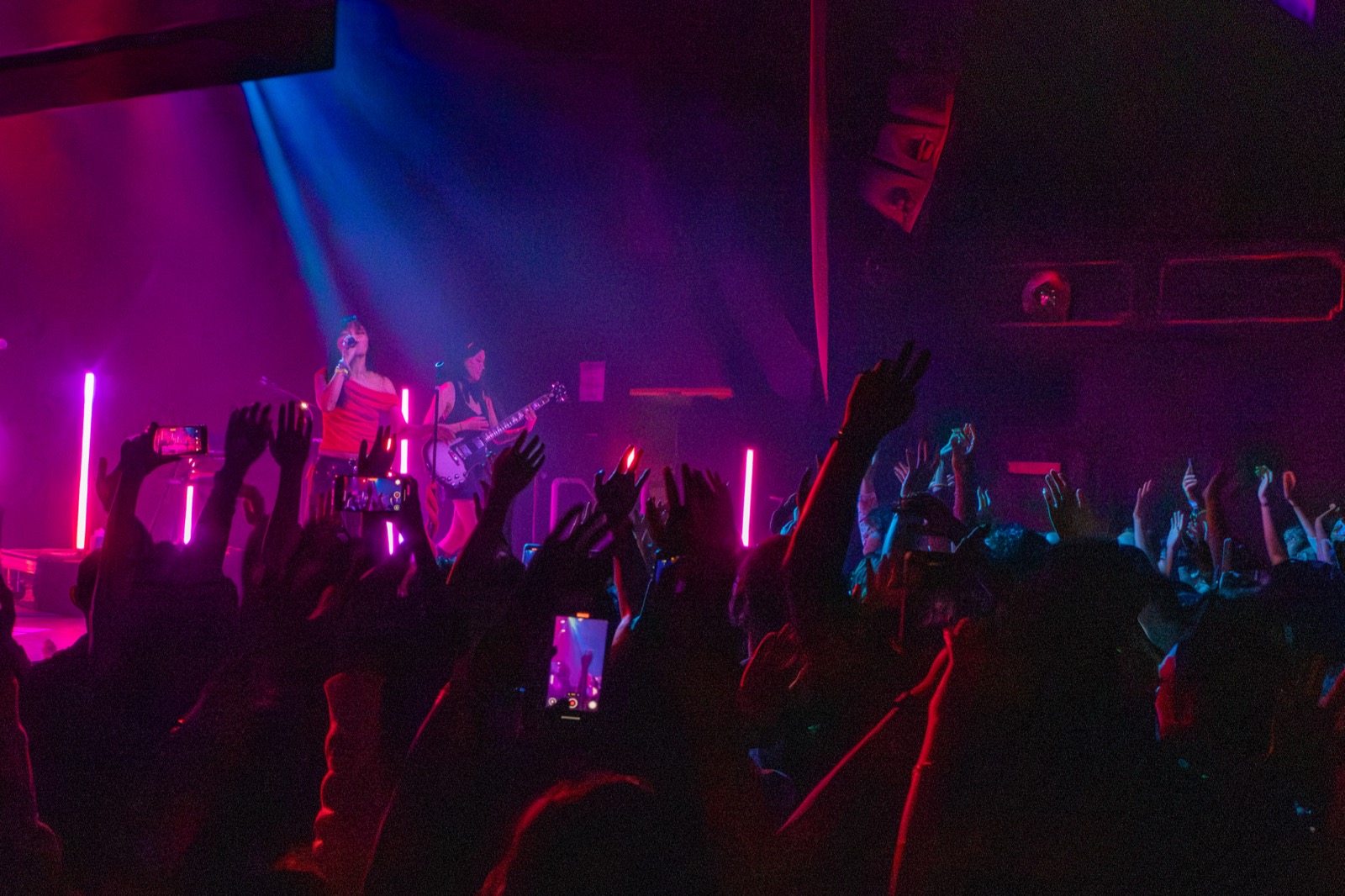 Crowd with raised hands and phones in front of the stage