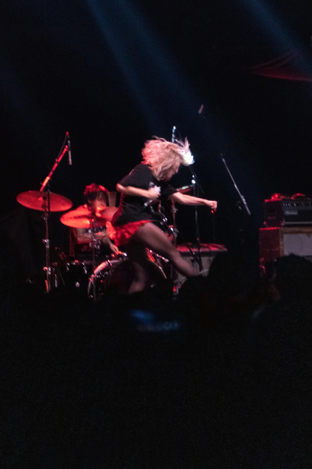 Guitarist mid-jump on stage in red light